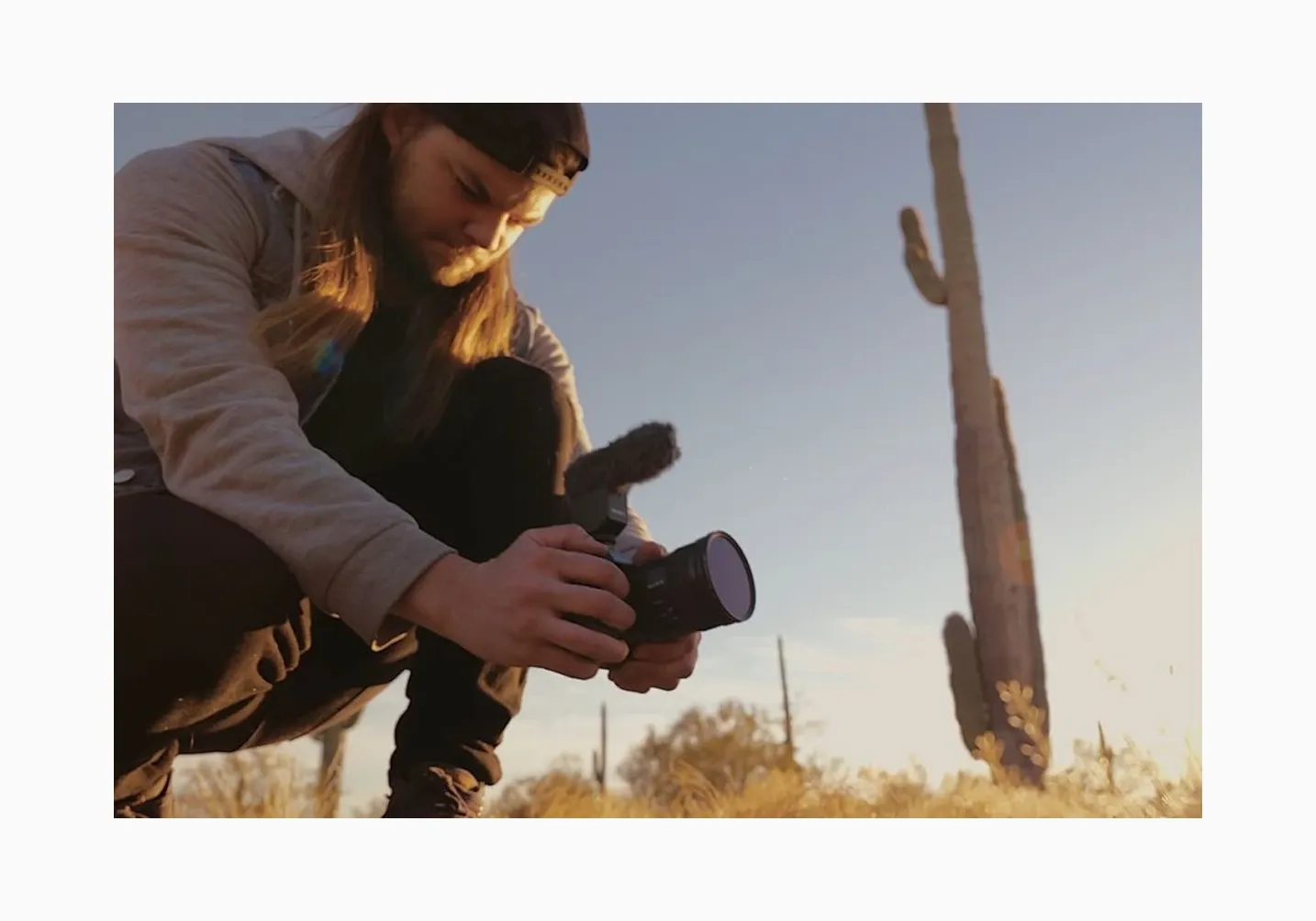 Travis J Film + Photo setting up camera in desert at golden hour, showcasing behind-the-scenes of outdoor photoshoot or landscape videography